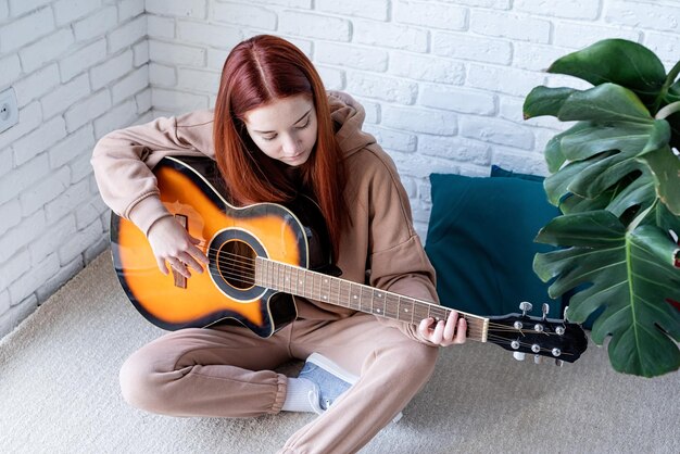Giovane donna che suona la chitarra a casa
