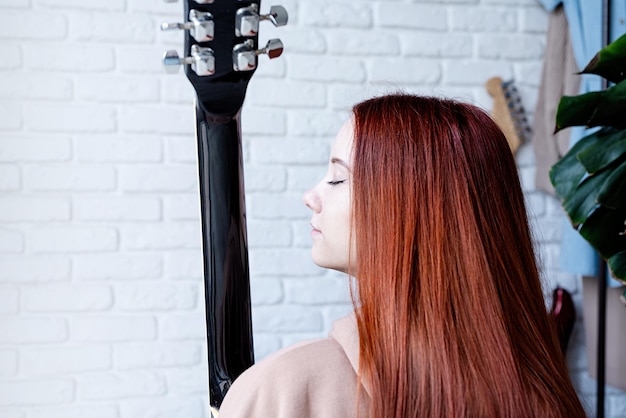 Giovane donna che suona la chitarra a casa