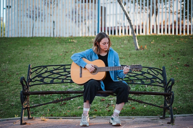 Giovane donna che suona la chitarra su una panchina