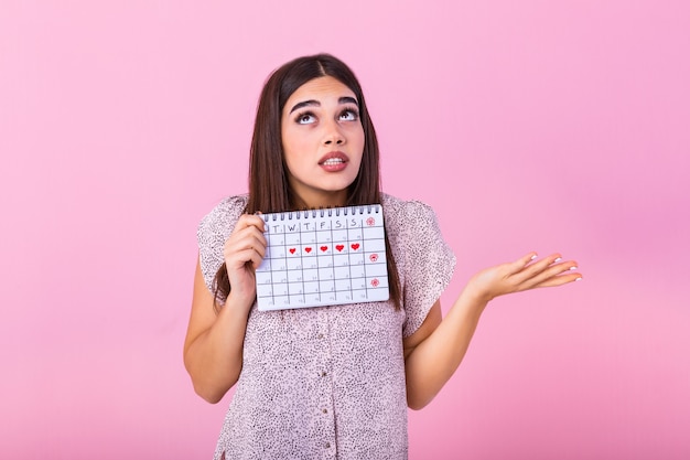 Giovane donna che tiene il calendario femminile periodi per il controllo dei giorni delle mestruazioni