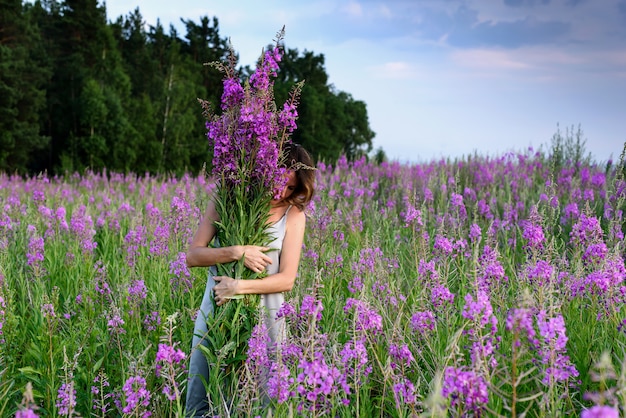 Giovane donna che tiene il mazzo di fiori rosa.