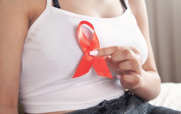 Giovane donna che tiene il nastro rosso HIV. AIDS. Sanità e medicina