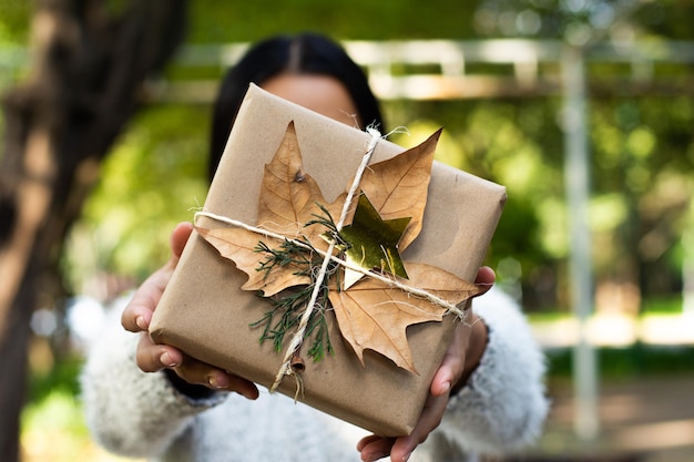 Giovane donna che tiene il regalo di natale avvolto organico