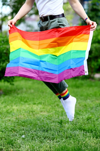 Giovane donna che tiene la bandiera LGBTQ in natura