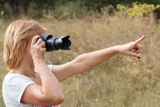 Giovane donna che tiene la fotocamera digitale e scatta foto del paesaggio estivo