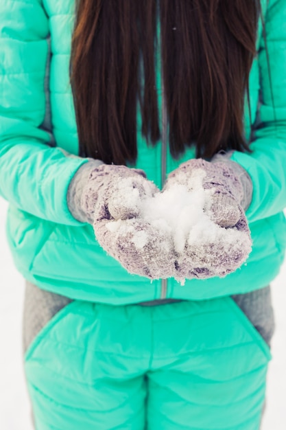 giovane donna che tiene la neve bianca e morbida naturale nelle sue mani per fare una palla di neve