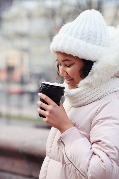 Giovane donna che tiene la tazza di caffè riutilizzabile in inverno