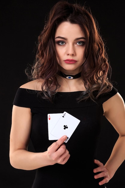 Giovane donna che tiene le carte da gioco su uno sfondo nero