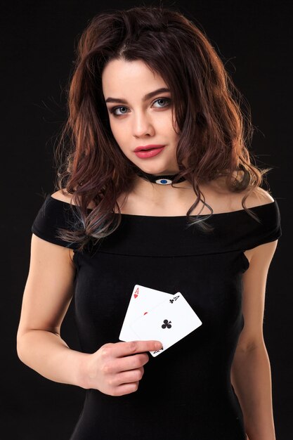 Giovane donna che tiene le carte da gioco su uno sfondo nero