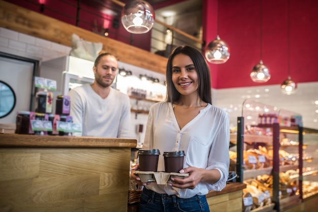 Giovane donna che tiene le tazze di caffè in un caffè