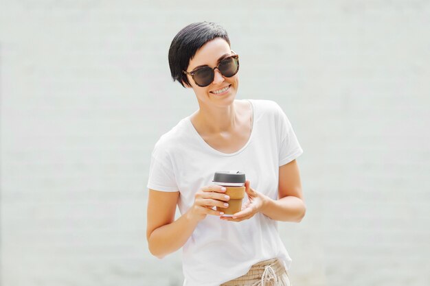Giovane donna che tiene tazza da caffè riutilizzabile. Stile di vita sostenibile. Concetto ecologico.