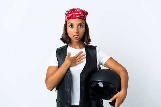 Giovane donna che tiene un casco da motociclista isolato su bianco sorpreso e scioccato mentre guarda a destra