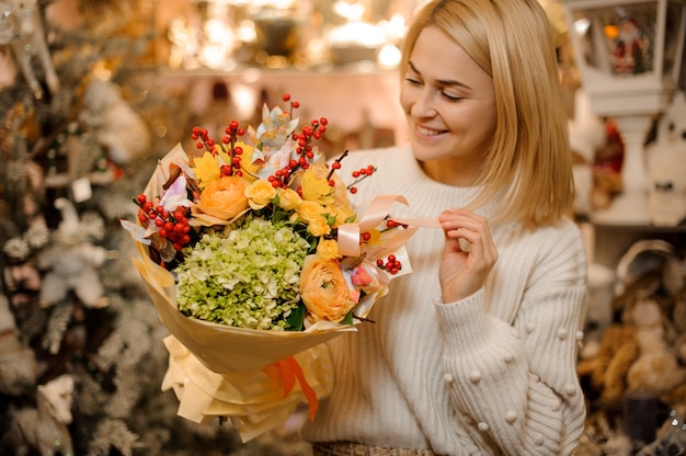 Giovane donna che tiene un mazzo di rose, ortensie e orchidee d'argento