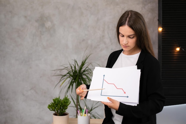 Giovane donna che tiene un segno con un simbolo di freccia di statistica decrescente