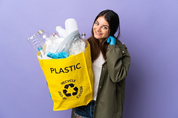 Giovane donna che tiene una borsa piena di bottiglie di plastica