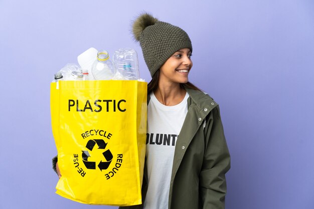 Giovane donna che tiene una borsa piena di plastica dall'aspetto laterale