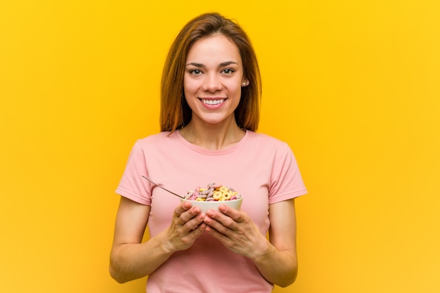 Giovane donna che tiene una ciotola di cereali felice, sorridente e allegra.