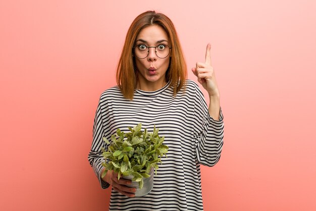 Giovane donna che tiene una pianta che ha qualche grande idea