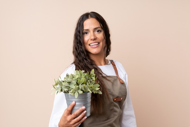 Giovane donna che tiene una pianta che sorride molto