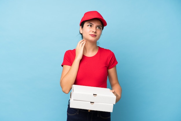 Giovane donna che tiene una pizza sopra la parete rosa isolata che pensa un'idea