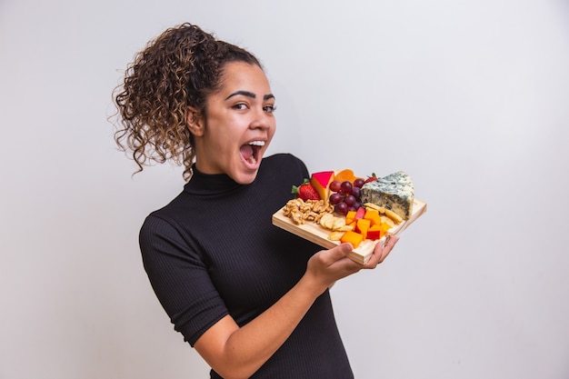 Giovane donna che tiene una tavola con vari tipi di snack al formaggio.