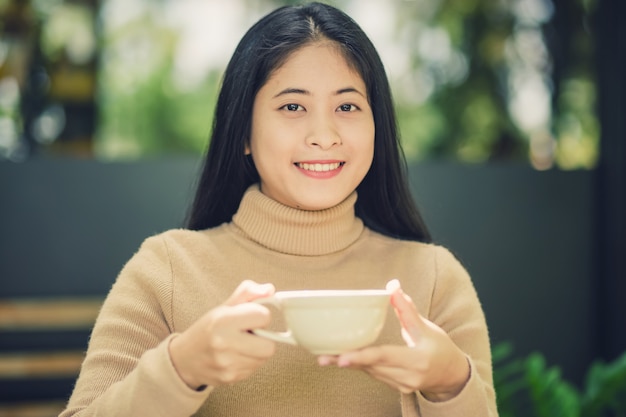 Giovane donna che tiene una tazza di caffè caldo nella vista della natura