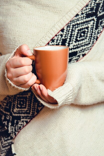 Giovane donna che tiene una tazza di caffè caldo nelle sue mani