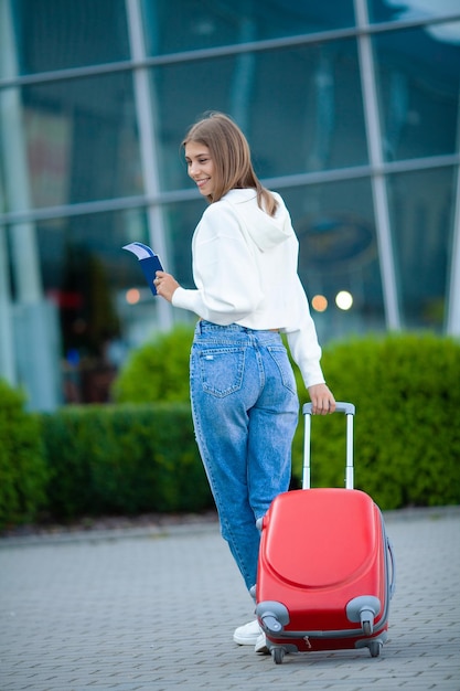 Giovane donna che tira la valigia nel terminal dell'aeroporto