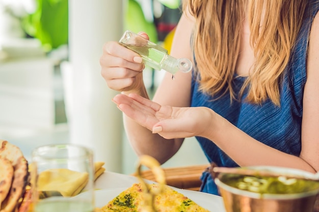 Giovane donna che usa il gel igienizzante per le mani nella caffetteria