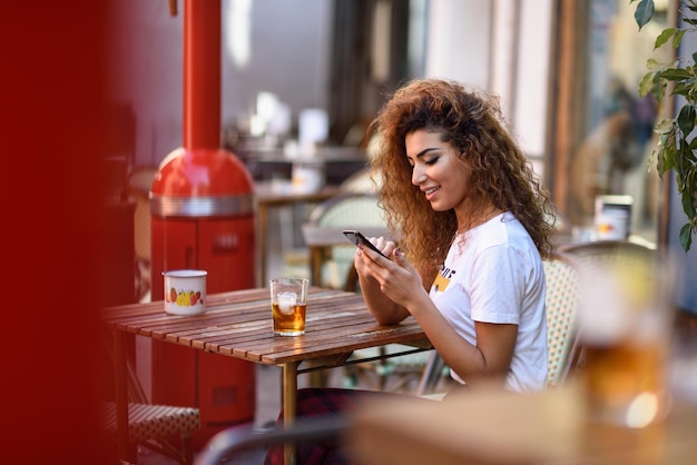 Giovane donna che usa il telefono al ristorante