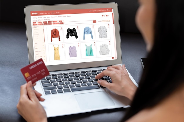 Giovane donna che usa un portatile con carta di credito per fare internet banking