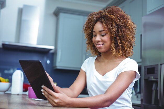 Giovane donna che utilizza compressa digitale nella cucina