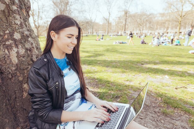 Giovane donna che utilizza computer al parco a Londra