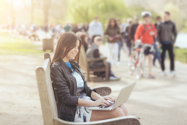 Giovane donna che utilizza computer al parco a Londra