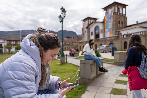 Giovane donna che utilizza il cellulare mentre è seduto su un parco urbano