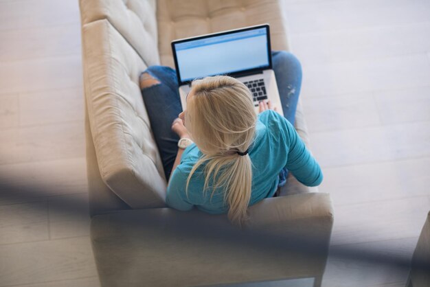 Giovane donna che utilizza il suo computer portatile nella sua lussuosa casa moderna, sorridente