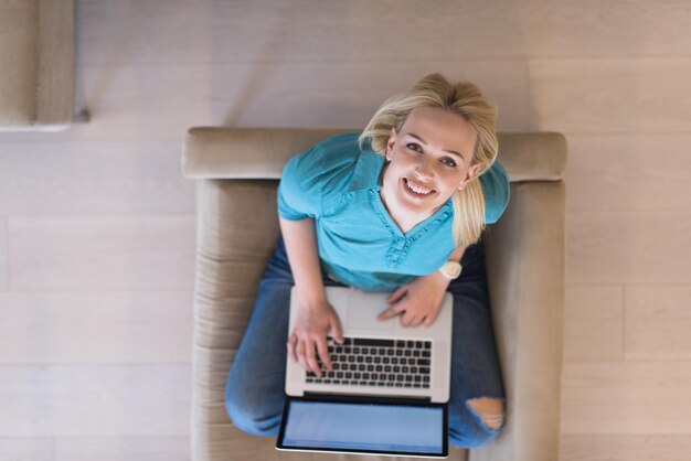 Giovane donna che utilizza il suo computer portatile nella sua vista dall'alto di casa moderna di lusso