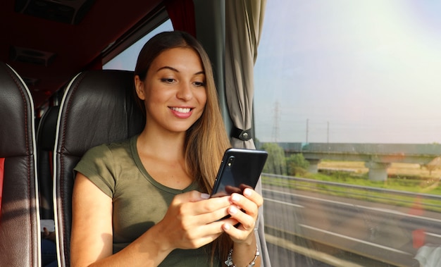 Giovane donna che utilizza il suo smartphone sulla vista banner bus