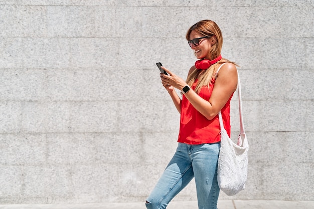 Giovane donna che utilizza il suo telefono cellulare in città.