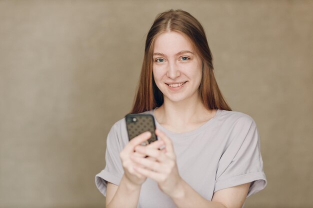 Giovane donna che utilizza il telefono cellulare a sfondo marrone