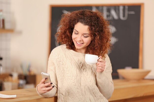 Giovane donna che utilizza il telefono cellulare all'interno