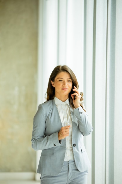 Giovane donna che utilizza il telefono cellulare dalla finestra dell'ufficio