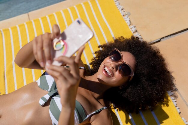 Giovane donna che utilizza il telefono cellulare vicino alla piscina