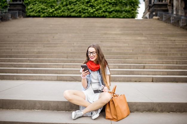 Giovane donna che utilizza il telefono seduto sulle grandi scale nella città di Dresda, Germany