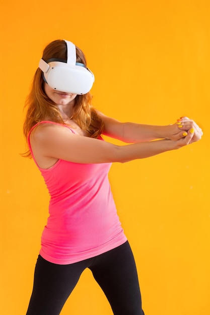 Giovane donna che utilizza l'auricolare per realtà virtuale isolato su sfondo arancione
