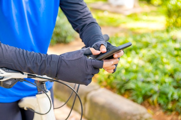 Giovane donna che utilizza lo smartphone mentre è seduto sulla sua bicicletta