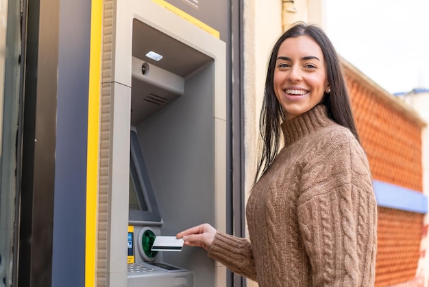 Giovane donna che utilizza un bancomat