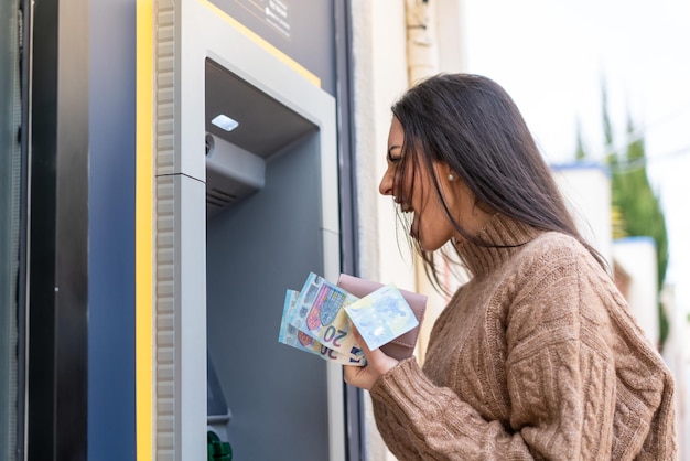 Giovane donna che utilizza un bancomat