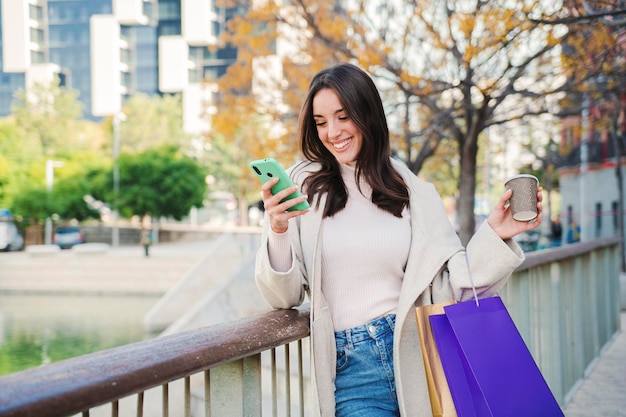 Giovane donna che utilizza un cellulare che invia un messaggio o un post con la tecnologia wireless di Internet