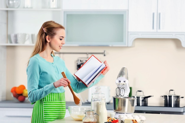 Giovane donna che utilizza un taccuino per seguire una ricetta